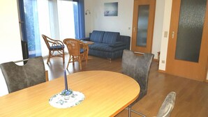 Ein Essbereich mit Holztisch und Stühlen, einem blauen Sofa und einer Tür mit satinierten Glasscheiben.