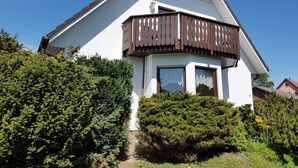Ein zweistöckiges Haus mit Balkon, umgeben von üppiger Vegetation.