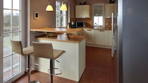 Una cucina moderna con isola centrale, sgabelli da bar, microonde e frigorifero.