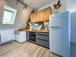 A modern kitchen with wooden cabinets, a white refrigerator, and a coffee machine. - Boddenblick in Vieregge by Interhome (Gingst)