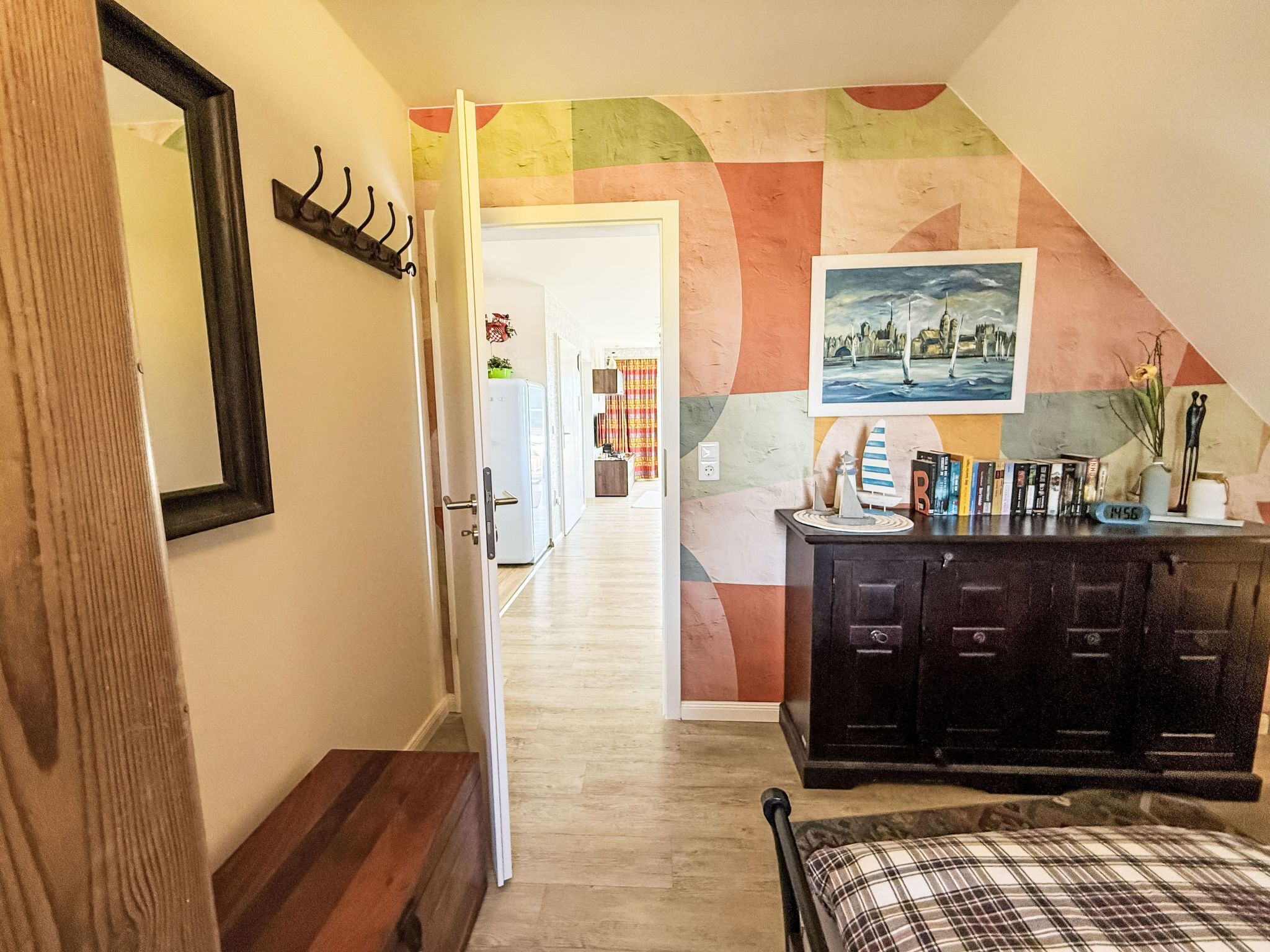 A bedroom with a bed, a dresser, a mirror, and a door leading to another room.