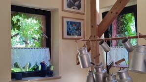 Ett kök med hängande kastruller och ett fönster med utsikt över grönskan.