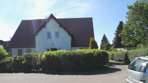 A two-story house with a red-tiled roof, a paved driveway, and a parked car. - Apartment Breege by Interhome (Breege)