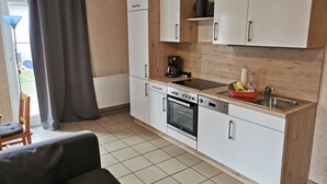 A compact kitchen with white cabinets, a built-in oven, a sink, and a coffee maker. - Apartment Breege by Interhome (Breege)