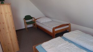 A small, simple room with a wooden bed, a chair, and a wooden wardrobe. - Juliusruh by Interhome (Breege)