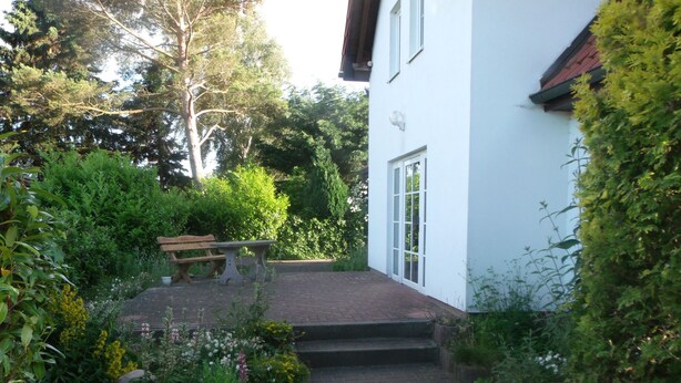A pathway leading to a white building with a red roof, surrounded by lush greenery and a bench. - Juliusruh by Interhome (Breege)