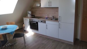 A compact kitchen with a dining table, chairs, a coffee maker, and a sink. - Juliusruh by Interhome (Breege)