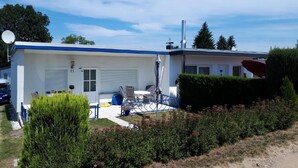 A single-story building with a white and blue exterior, a garage door, and a satellite dish. - in Tarnewitz mit Terrasse und Grill by Interhome (Boltenhagen)