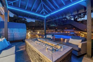 Eine Terrassengrundstück mit einem Steinkamin, Sitzgelegenheiten und einem Poolbereich.