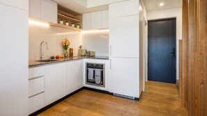Una cucina moderna con mobili bianchi, forno integrato e pavimento in legno.
