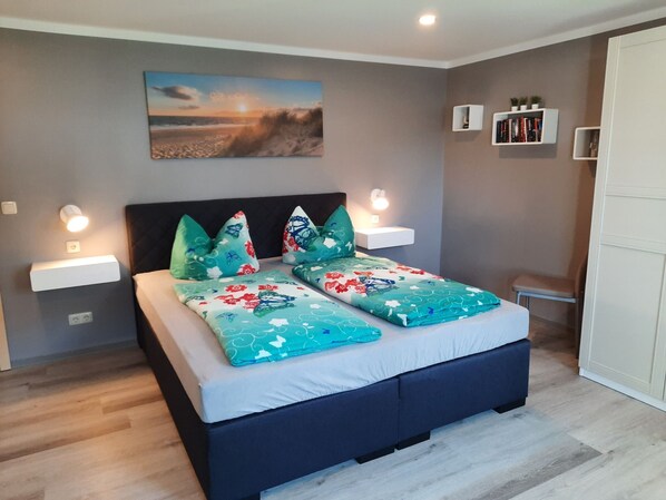 Un dormitorio moderno con una cama, mesitas de noche, un estante en la pared y un cuadro.