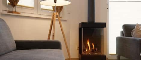 A modern living room with a sofa, a floor lamp, and a wood-burning stove.