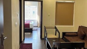 A hotel room with a bed, a sofa, a desk, and a ceiling fan. - Jagannath Puri Beach Stay (Brahmagiri)