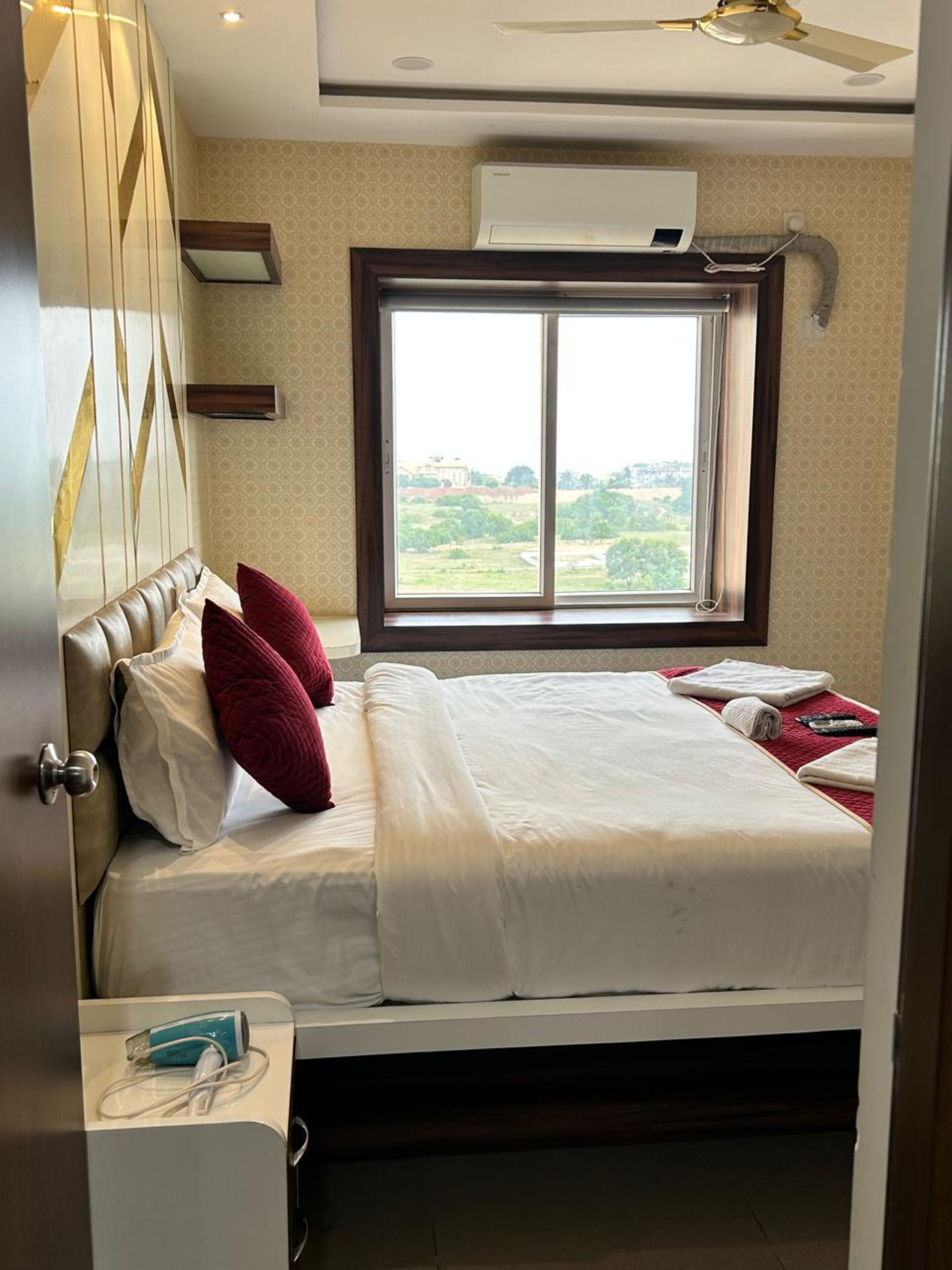Ein Hotelzimmer mit Bett, Fenster mit Blick, Klimaanlage und Deckenventilator.