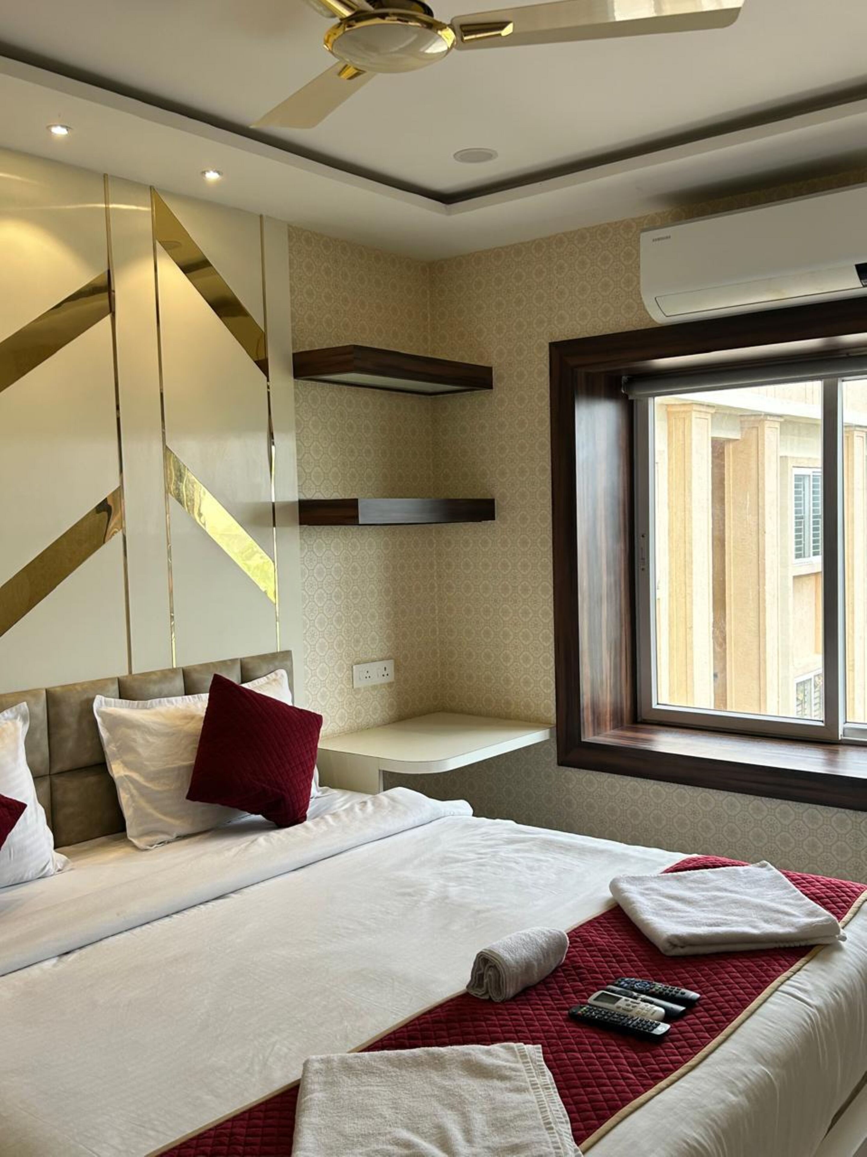 Une chambre d’hôtel avec un lit, une fenêtre donnant sur un paysage agréable, un ventilateur de plafond et un climatiseur fixé au mur.