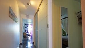 Un couloir avec un miroir, une horloge et une porte donnant sur une salle de bain.