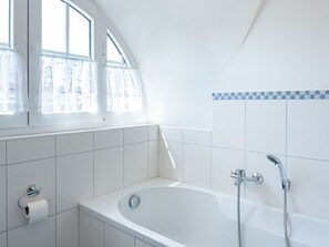 Un baño moderno con una bañera independiente, ducha y dispensador de papel higiénico.