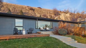A modern house with a deck, outdoor seating, and a stone pathway leading to the entrance.