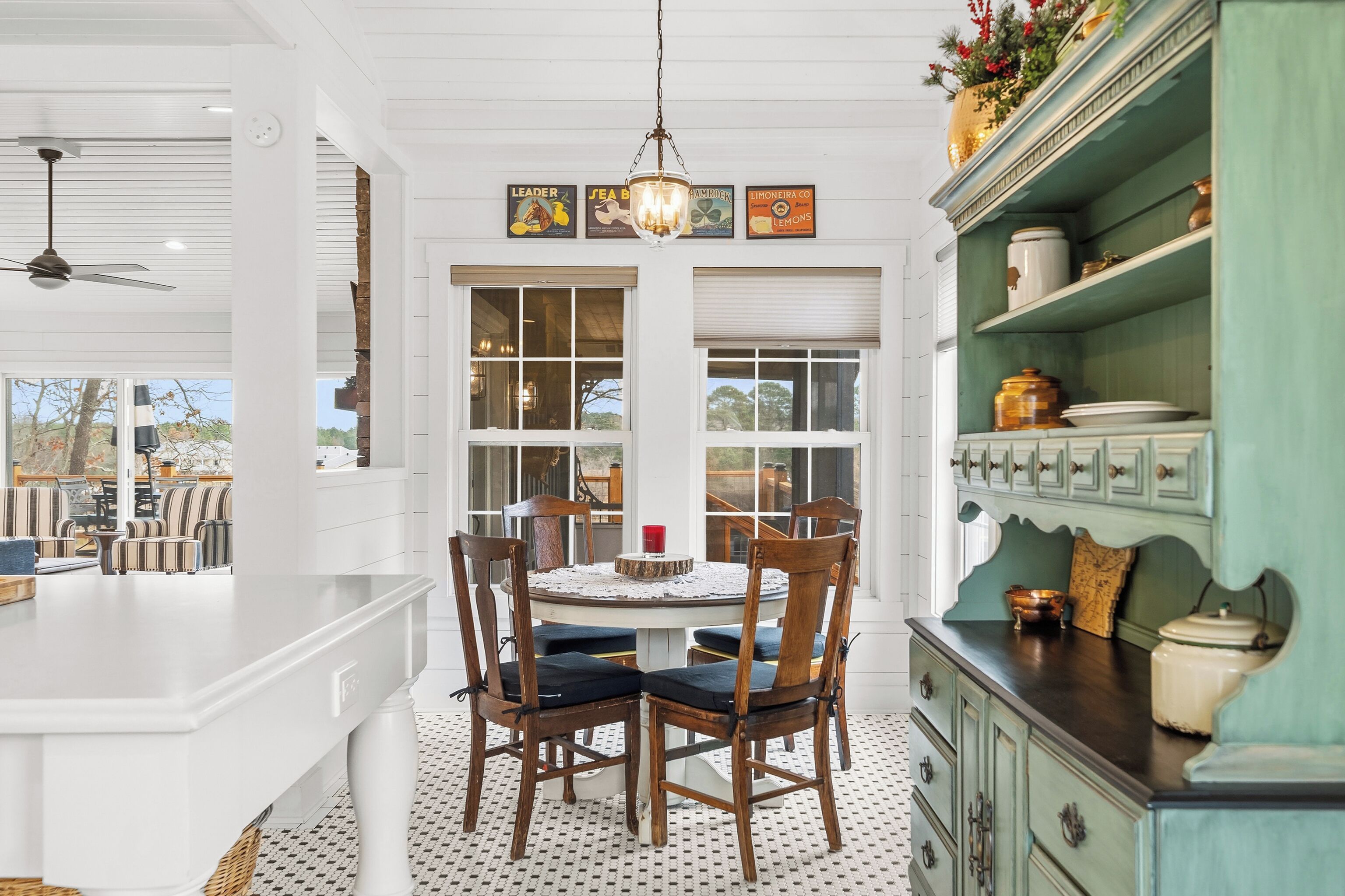 A dining area with a round table, wooden chairs, and a hanging light fixture.