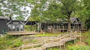 A rustic cabin-style building with a covered porch and a wooden deck. - Lake Hamilton Retreat, Main House, Guest House, Sleeps Up to 14, Private Dock (Hot Springs)