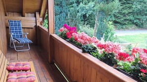 A wooden deck with a bench, a chair, and a flower planter. - FeWo Steinbeisser by Interhome (Arrach)