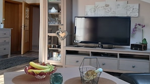 A modern living room with a flat-screen TV, wooden cabinets, and decorative wall art. - FeWo Steinbeisser by Interhome (Arrach)