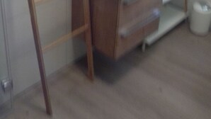 Ein Badezimmer mit einer Holzleiter, die an der Wand lehnt, einem runden Spiegel und einem weißen Waschbecken mit modernem Design.
