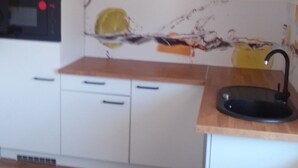 Eine Küche mit weißen Schränken, einer Holz Arbeitsplatte, einem schwarzen Spülbecken und einer Mikrowelle.
