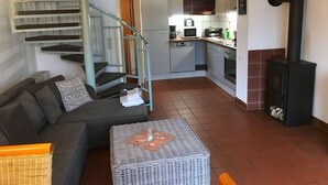 A modern living room with a grey sofa, a wicker coffee table, and a staircase with blue railings leading to a kitchen area. - Charmantes Ferienhaus in Zandt mit Garten by Interhome (Zandt)