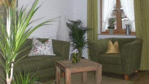 A living room with two green sofas, a wooden coffee table, and a large window with curtains. - Alpspitzblick by Interhome (Garmisch-Partenkirchen)
