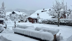 A snow-covered landscape with a wooden bench and a brick wall. - Alpspitzblick by Interhome (Garmisch-Partenkirchen)