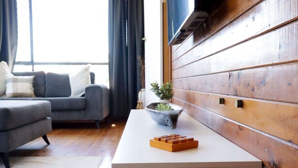 A modern living room with a grey sofa, a white coffee table, and a wooden accent wall.