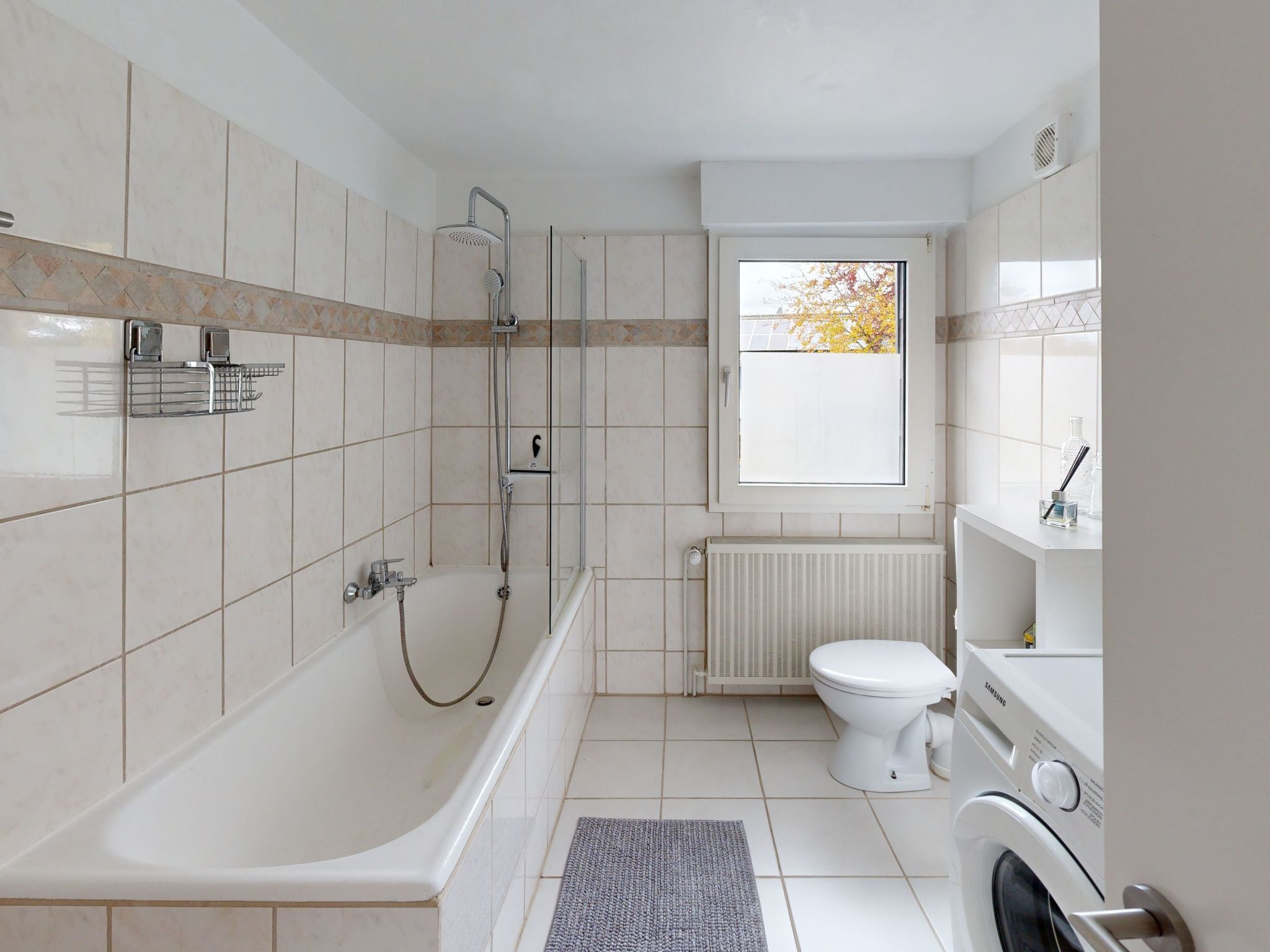 Ein modernes Badezimmer mit Badewanne, Dusche, Toilette und einem Fenster mit Blick.