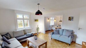 Ein modernes Wohnzimmer mit einer Couch, einem Couchtisch und einem Essbereich mit Tisch und Stühlen.