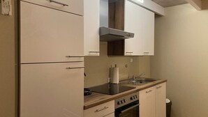 Een moderne keuken met witte kastjes, een houten aanrechtblad, een ingebouwde oven en een roestvrijstalen spoelbak.