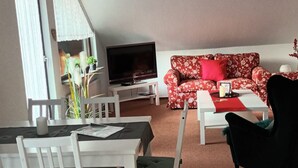 Una sala de estar con sofá, televisor y comedor con mesa y sillas.