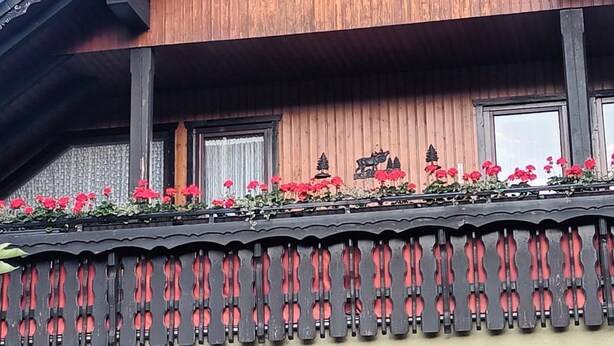 Un edificio de madera con balcón, ventanas y detalles decorativos.