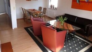 Ein Essbereich mit einem Holztisch, roten Stühlen und einem schwarzen Sofa.