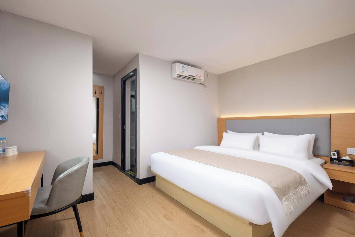 A hotel room with a bed, a desk, a chair, and a wardrobe.