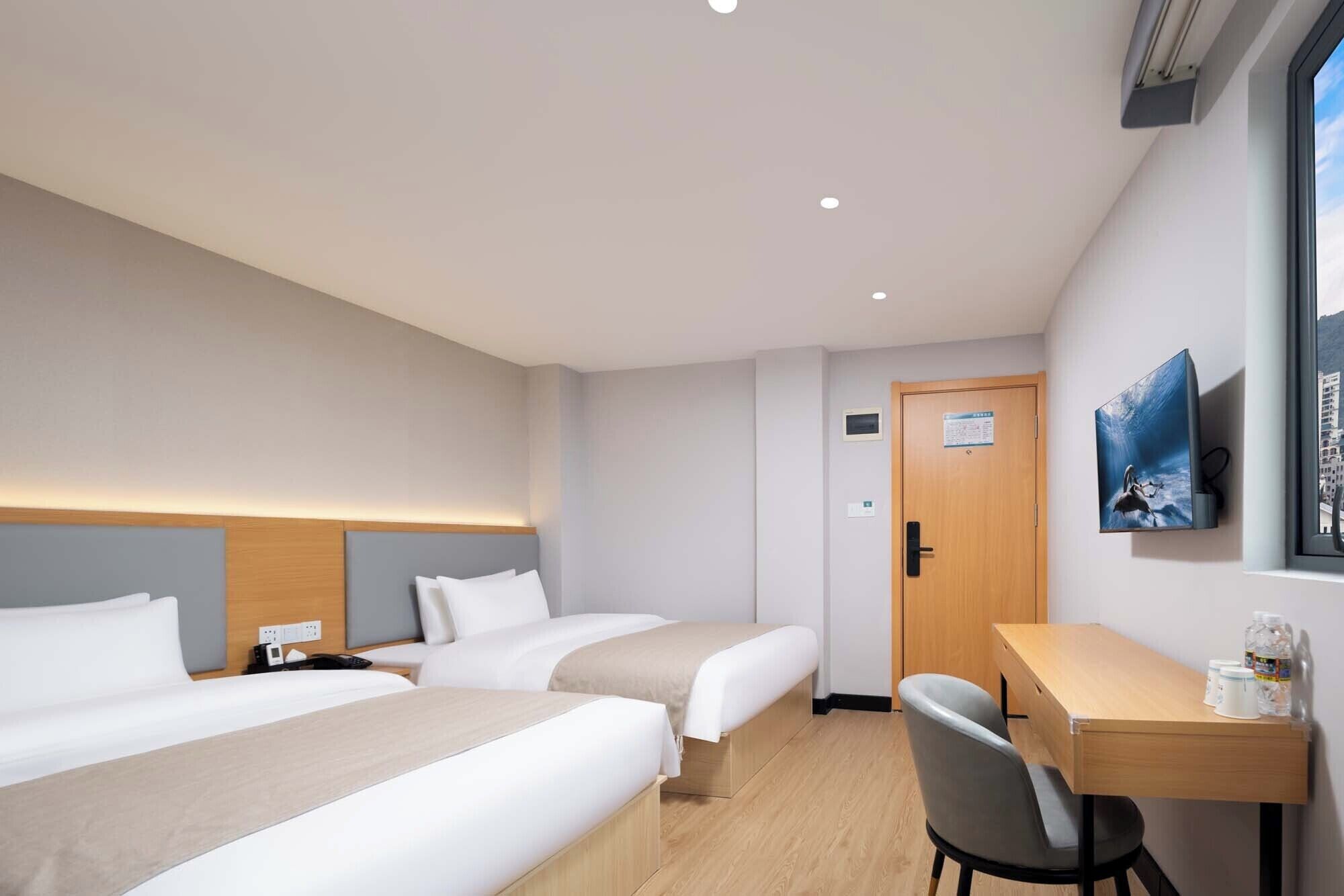 A hotel room with two beds, a desk, and a chair.