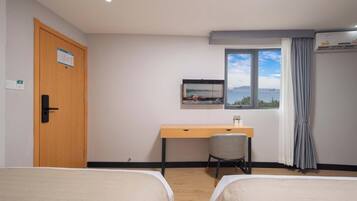 Habitación de hotel con dos camas, un escritorio, una silla, una ventana con vistas y un aire acondicionado.