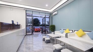 A modern waiting area with a reception desk, seating, and a view of the parking lot. - Sanya Guanhailou Hotel (Sanya)
