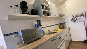 Una cocina moderna con armarios blancos, encimera de madera, horno empotrado y cafetera.