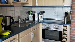 Una cocina compacta con armarios de madera clara, un horno de acero inoxidable y una encimera azul.