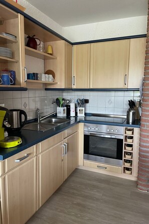 A compact kitchen with light wood cabinets, a stainless steel oven, and a blue countertop. - Sehnsucht Nordsee, by Interhome (Burhave)