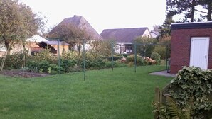 Un giardino curato con prato, diverse piante e una struttura in mattoni.