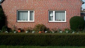 Una casa in mattoni rossi con tre finestre e un piccolo balcone.