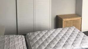 Une chambre à coucher comprenant un lit, une armoire, un téléviseur et un petit tabouret en bois.