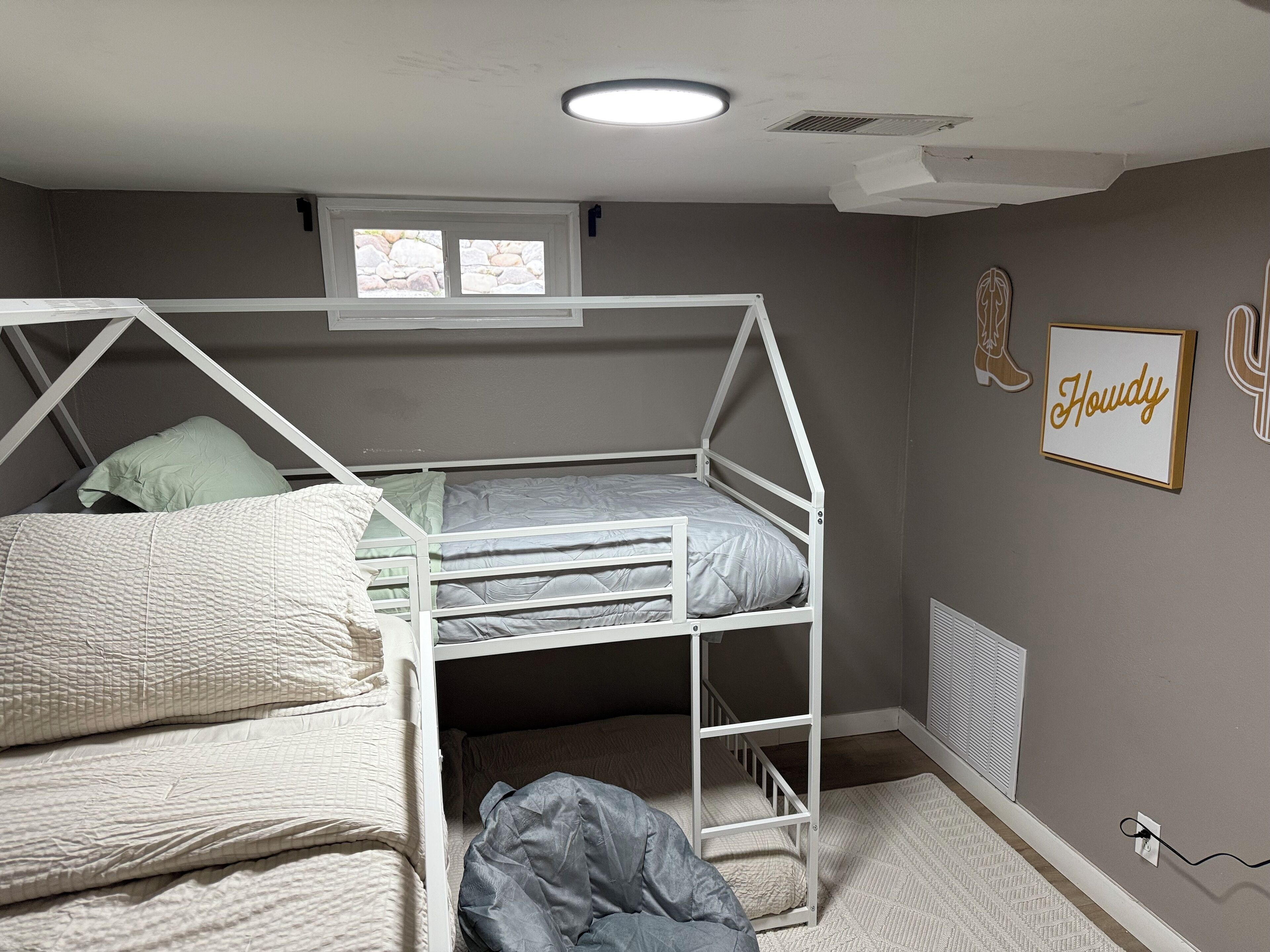 Camera con letto a castello, finestra sopra e una scritta incorniciata al muro.