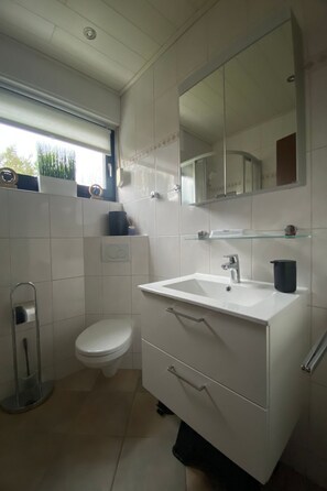 Une salle de bain moderne avec un lavabo blanc, un miroir et des toilettes.